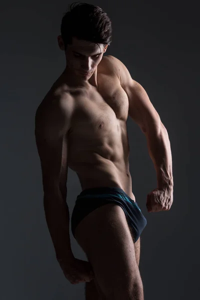 Young male athlete bodybuilder posing. Handsome athletic male power guy. Fitness muscular person. Young athlete showing muscles in the studio. six packs muscles posing shirtless on gray background — Stock Photo, Image