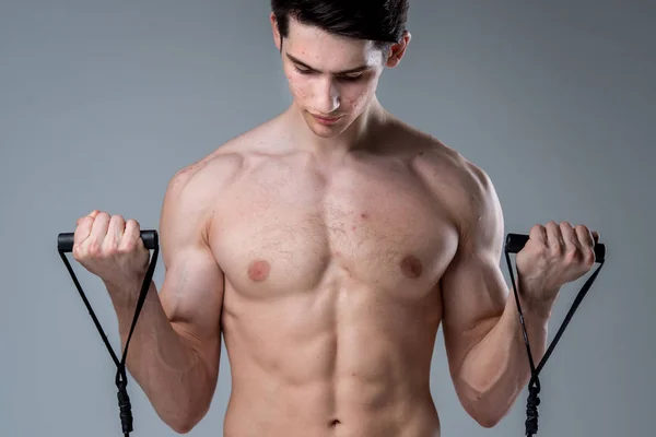 Studio portrait young Caucasian man on gray background posing. theme of puberty, problem skin, teen acne. Caucasian athlete uses banding for fitness. Allergy sports nutrition, supplements steroids — ストック写真