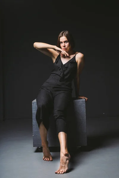Jovem modelo feminino caucasiano posando em estúdio fundo preto.Menina sentada em um vestido preto em uma parede escura. Sujeito mau estado psicológico grave, intra, problemas, conflito de personalidade — Fotografia de Stock