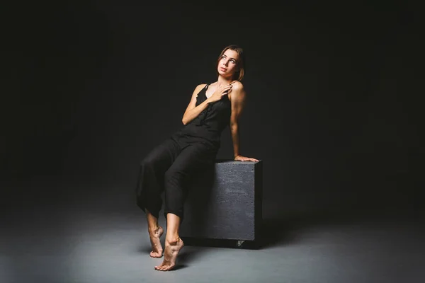 Young Caucasian female model posing in studio black background.Girl sitting in a black dress on a dark wall. Subject severe poor psychological state, intra, problems, personality conflict — 스톡 사진