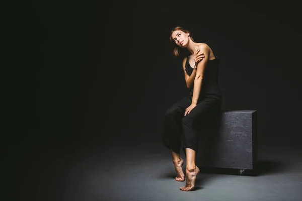 Young Caucasian female model posing in studio black background.Girl sitting in a black dress on a dark wall. Subject severe poor psychological state, intra, problems, personality conflict — 스톡 사진
