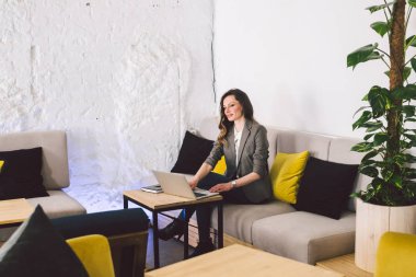 İş yerinde konsantre oldu. Kendine güvenen genç yetişkin orta yaşlı kadın akıllı rahat giysiler içinde, bir dizüstü bilgisayar üzerinde çalışan, yaratıcı bir ofis veya kafe içinde oturan. Tema iş kadını boş alanda çalışmak