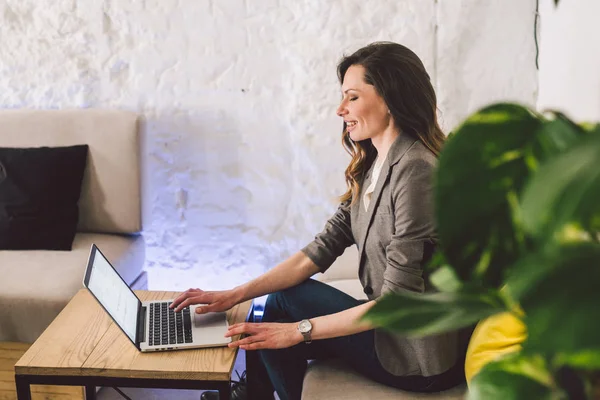 Concentrado no trabalho. Mulher de meia-idade adulta jovem confiante em roupas casuais inteligentes, trabalhando em um laptop, sentado dentro de um escritório criativo ou café. Tema mulher de negócios trabalhar no espaço livre — Fotografia de Stock