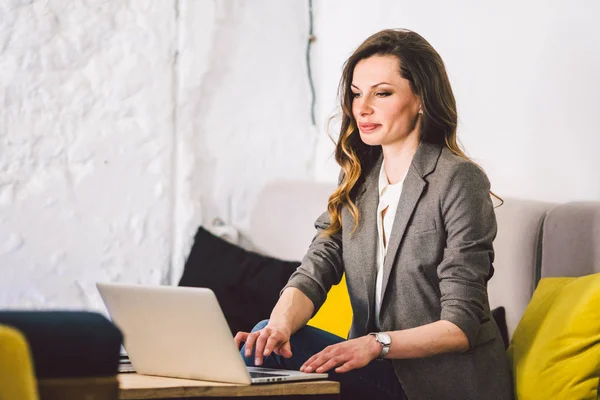 Concentrado no trabalho. Mulher de meia-idade adulta jovem confiante em roupas casuais inteligentes, trabalhando em um laptop, sentado dentro de um escritório criativo ou café. Tema mulher de negócios trabalhar no espaço livre — Fotografia de Stock