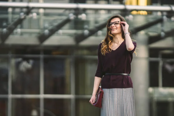 Mujer de negocios parada en la calle contra el edificio de oficinas. Mujer de negocios de la ciudad trabajando. Mujer de negocios retrato sonriendo con gafas. Mujer posando fuera de oficina edificio verano traje de negocios — Foto de Stock