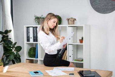 Tema iş kadını iş başında. Kağıt üzerinde düzenlemeler finansal grafikler kontrol ofiste, tabloda kenarında oturan çalışma güzel genç seksi beyaz kadın iş adamı