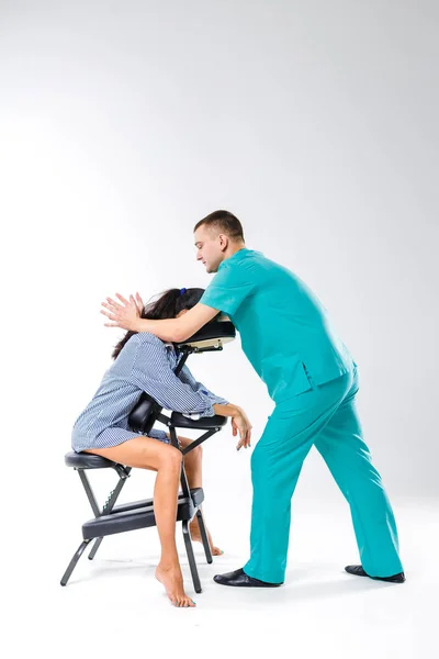 Tema masaje y oficina. Terapeuta masculino con traje azul haciendo masaje de espalda y cuello para trabajadora joven, mujer de negocios con camisa en silla de masaje shiatsu — Foto de Stock