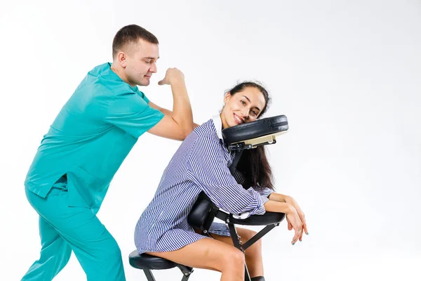 Tema masaje y oficina. Terapeuta masculino con traje azul haciendo masaje de espalda y cuello para trabajadora joven, mujer de negocios con camisa en silla de masaje shiatsu — Foto de Stock