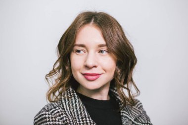 Portre beyaz arka plan üzerinde genç güzel beyaz kadın. Avrupalı kız modeli stüdyoda duvar arka plan poz. Ceket ve gülümseme ve kıvırcık dalgalı saçlı siyah balıkçı yaka İş kadını