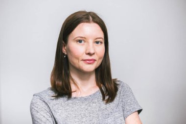 beyaz stüdyo arka plan üzerinde gri t-shirt gülümseyen şık genç güzel Kafkas kadın portresi, izole, doğal bir görünüm, uzun kahverengi saçlı