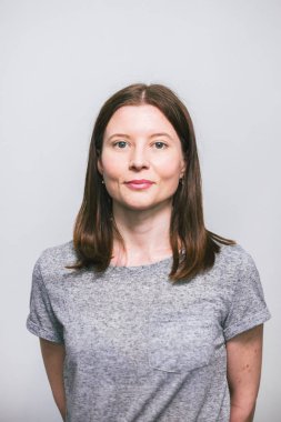 beyaz stüdyo arka plan üzerinde gri t-shirt gülümseyen şık genç güzel Kafkas kadın portresi, izole, doğal bir görünüm, uzun kahverengi saçlı