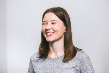 beyaz stüdyo arka plan üzerinde gri t-shirt gülümseyen şık genç güzel Kafkas kadın portresi, izole, doğal bir görünüm, uzun kahverengi saçlı