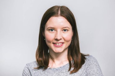 beyaz stüdyo arka plan üzerinde gri t-shirt gülümseyen şık genç güzel Kafkas kadın portresi, izole, doğal bir görünüm, uzun kahverengi saçlı