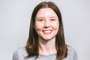 beyaz stüdyo arka plan üzerinde gri t-shirt gülümseyen şık genç güzel Kafkas kadın portresi, izole, doğal bir görünüm, uzun kahverengi saçlı