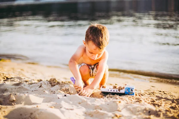 Los niños juegan en la playa. Juguete de arena y agua. Camión coche de juguete con arena y tierra. medio ambiente verde equipo de construcción en el trabajo, concepto de construcción. símbolos industrail . —  Fotos de Stock