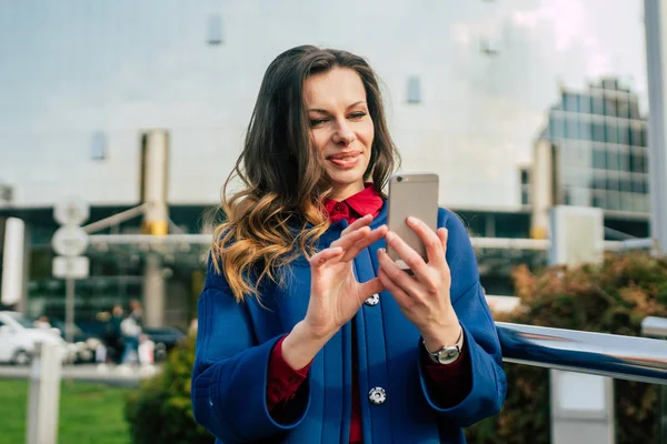 Edifici per uffici gente di città in giacca e cravatta. Donna d'affari caucasica utilizzando smartphone con mano. Concetto aziendale. Ritratto elegante donna d'affari in abiti alla moda che tiene il telefono vicino all'edificio dell'ufficio — Foto Stock