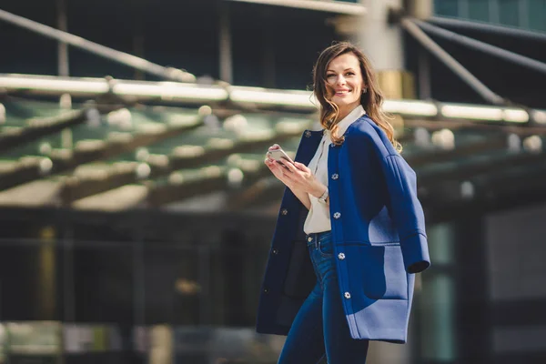 Edifícios de escritórios pessoas da cidade de terno. Mulher de negócios caucasiana usando smartphone com a mão. Conceito de negócio. Retrato mulher de negócios elegante em roupas elegantes segurando telefone perto de prédio de escritórios — Fotografia de Stock