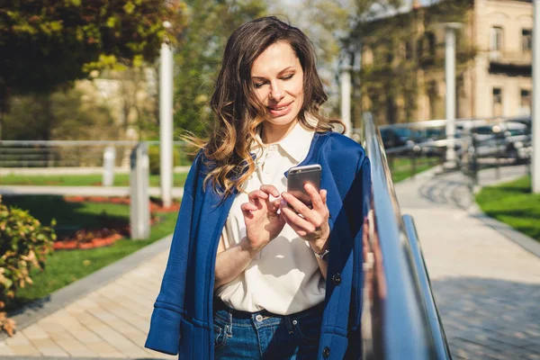 Edifícios de escritórios pessoas da cidade de terno. Mulher de negócios caucasiana usando smartphone com a mão. Conceito de negócio. Retrato mulher de negócios elegante em roupas elegantes segurando telefone perto de prédio de escritórios — Fotografia de Stock