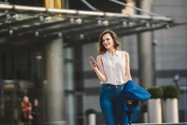 Edifícios de escritórios pessoas da cidade de terno. Mulher de negócios caucasiana usando smartphone com a mão. Conceito de negócio. Retrato mulher de negócios elegante em roupas elegantes segurando telefone perto de prédio de escritórios — Fotografia de Stock