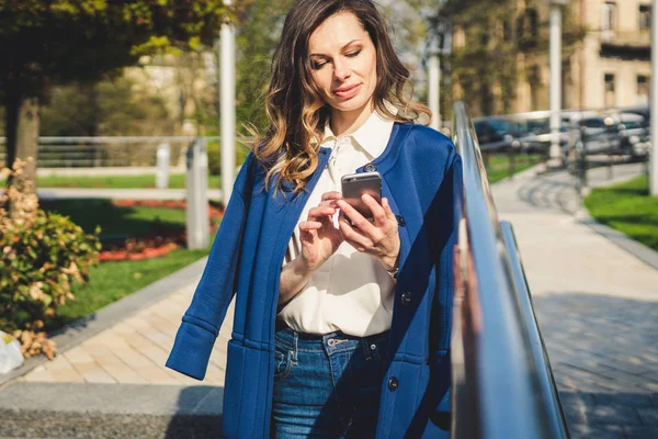 Edifici per uffici gente di città in giacca e cravatta. Donna d'affari caucasica utilizzando smartphone con mano. Concetto aziendale. Ritratto elegante donna d'affari in abiti alla moda che tiene il telefono vicino all'edificio dell'ufficio — Foto Stock