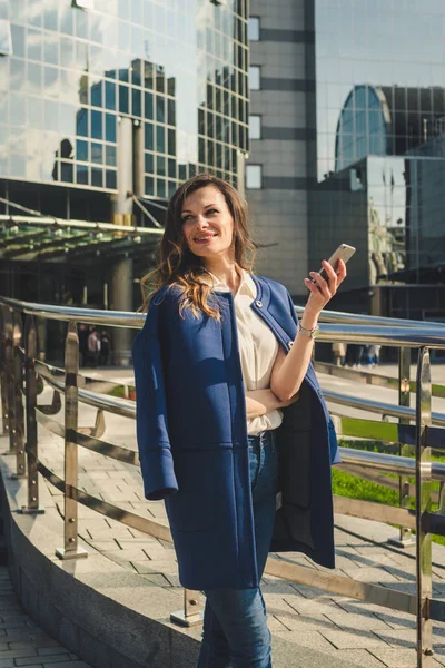 Office buildings city people in suit. Caucasian businesswoman using smartphone with hand. Business concept. Portrait stylish business woman in fashionable clothes holding Phone near office building