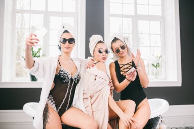 Spa'daki mutlu arkadaş grubunu gösteren resim. kafalarında havlu olan kızlar eğlenir ve evde selfie çekerler. Dostluk, kozmetik, pijama partisi konsepti. Otelde bir gelin ile Hen parti