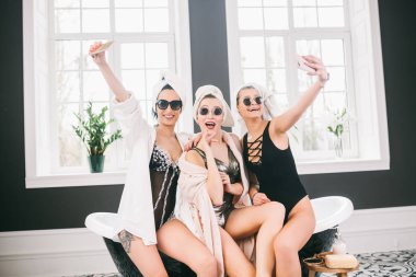 Spa'daki mutlu arkadaş grubunu gösteren resim. kafalarında havlu olan kızlar eğlenir ve evde selfie çekerler. Dostluk, kozmetik, pijama partisi konsepti. Otelde bir gelin ile Hen parti