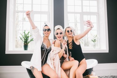 Spa'daki mutlu arkadaş grubunu gösteren resim. kafalarında havlu olan kızlar eğlenir ve evde selfie çekerler. Dostluk, kozmetik, pijama partisi konsepti. Otelde bir gelin ile Hen parti