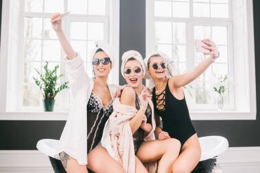 Spa'daki mutlu arkadaş grubunu gösteren resim. kafalarında havlu olan kızlar eğlenir ve evde selfie çekerler. Dostluk, kozmetik, pijama partisi konsepti. Otelde bir gelin ile Hen parti