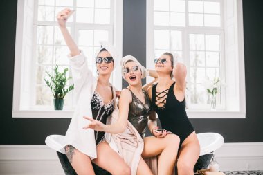 Spa'daki mutlu arkadaş grubunu gösteren resim. kafalarında havlu olan kızlar eğlenir ve evde selfie çekerler. Dostluk, kozmetik, pijama partisi konsepti. Otelde bir gelin ile Hen parti
