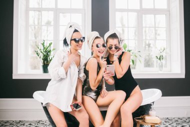 Spa'daki mutlu arkadaş grubunu gösteren resim. kafalarında havlu olan kızlar eğlenir ve evde selfie çekerler. Dostluk, kozmetik, pijama partisi konsepti. Otelde bir gelin ile Hen parti