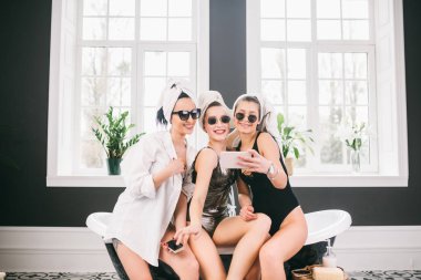 Spa'daki mutlu arkadaş grubunu gösteren resim. kafalarında havlu olan kızlar eğlenir ve evde selfie çekerler. Dostluk, kozmetik, pijama partisi konsepti. Otelde bir gelin ile Hen parti