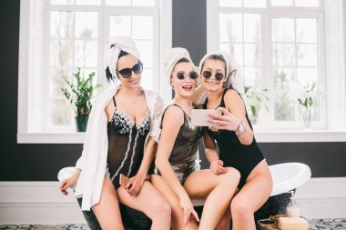 Spa'daki mutlu arkadaş grubunu gösteren resim. kafalarında havlu olan kızlar eğlenir ve evde selfie çekerler. Dostluk, kozmetik, pijama partisi konsepti. Otelde bir gelin ile Hen parti