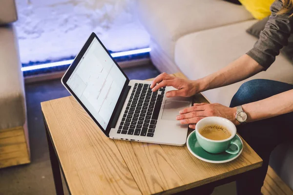 クローズアップビジネスウーマンは、カップコーヒーとラップトップを使用して手。喫茶店でキーボードコンピュータを入力する女性の手。テーブルの中のスマートフォンとホットカップカプチーノ。人々のライフスタイルの概念。フリーランスのテーマ — ストック写真