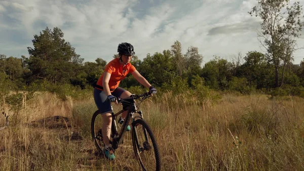 Молодая спортсменка-кавказка, катающаяся на горных велосипедах на прекрасном поле перьевой травы. Приключения и путешествия. Спорт, Велоспорт в Медоу. велосипедист на велосипеде в природном ландшафте — стоковое фото