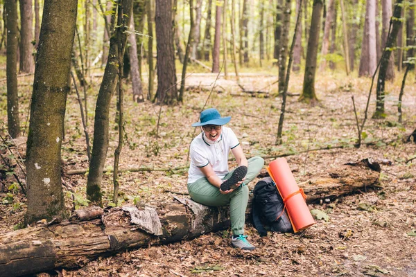 Jonge vrouw die moeite heeft om kniepijn te voelen tijdens het reizen in het bos. Letsel op weg naar kamp. vrouwelijke toerist kreeg beenletsel in bos en wordt gekwetst. Gezondheidsprobleem in de reis. Thema verzekeringsbedrijf — Stockfoto