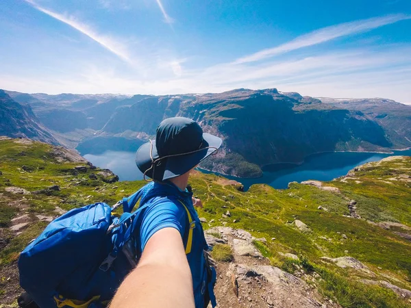 特罗尔通加附近的环塔瓦特内湖。挪威的蓝湖。戴帽子和背包的女游客退后，手里拿着相机在背景山和湖自然拍摄自拍照片 — 图库照片