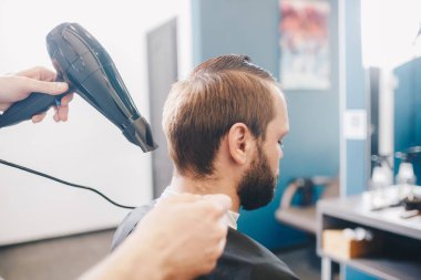 genç sakallı adam saç kurutma berber dükkanı ile bakımlı kuaför oluyor. Profesyonel Kuaför Kurutma Saç Yakışıklı Müşteri. Kuaför Salonunda Çalışan Profesyonel Berber, Saç Kurutma Makinesi Kullan