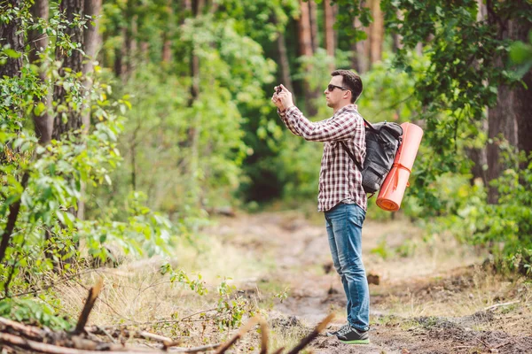 Man hiker taking photo smart phone in forest. Attractive Traveler Making Photo With Mobile Phone. Traveler hiker man with backpack hiking in nature, tourist backpacker use camera. vacation concept — Stock Photo, Image