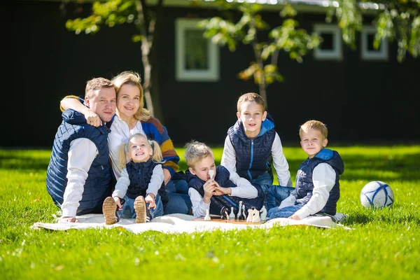 Grote familie ontspannen in groene natuur. Gelukkig familie portret op buiten, groep zes mensen zitten op gras, zomerseizoen, kind en ouder. Kinderen, ouderschap en natuur concept. picknick buiten op gazon — Stockfoto