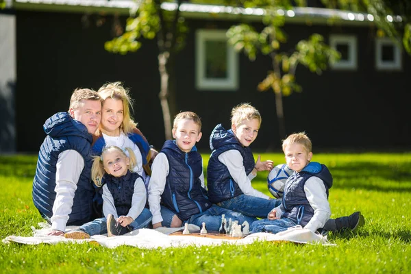 Grote familie ontspannen in groene natuur. Gelukkig familie portret op buiten, groep zes mensen zitten op gras, zomerseizoen, kind en ouder. Kinderen, ouderschap en natuur concept. picknick buiten op gazon — Stockfoto