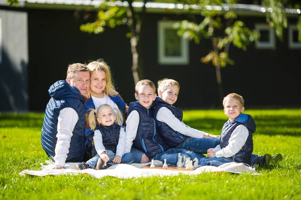 Grote familie ontspannen in groene natuur. Gelukkig familie portret op buiten, groep zes mensen zitten op gras, zomerseizoen, kind en ouder. Kinderen, ouderschap en natuur concept. picknick buiten op gazon — Stockfoto