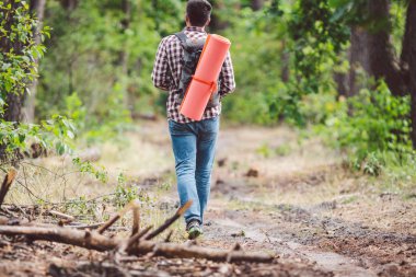 Kavram nefes kesen yolculuk ve macera. Sırt çantası ile geri görünüm yürüyüş cesur Kafkas adam kırsal yol boyunca ormana yürüyor. Tema turizm ve açık hava etkinlikleri. backpacker orman geçer