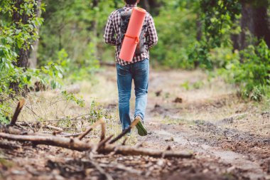 Kavram nefes kesen yolculuk ve macera. Sırt çantası ile geri görünüm yürüyüş cesur Kafkas adam kırsal yol boyunca ormana yürüyor. Tema turizm ve açık hava etkinlikleri. backpacker orman geçer