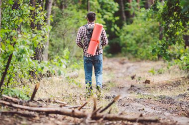 Kavram nefes kesen yolculuk ve macera. Sırt çantası ile geri görünüm yürüyüş cesur Kafkas adam kırsal yol boyunca ormana yürüyor. Tema turizm ve açık hava etkinlikleri. backpacker orman geçer