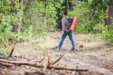 Kavram nefes kesen yolculuk ve macera. Sırt çantası ile geri görünüm yürüyüş cesur Kafkas adam kırsal yol boyunca ormana yürüyor. Tema turizm ve açık hava etkinlikleri. backpacker orman geçer