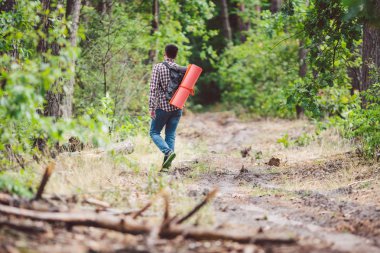 Kavram nefes kesen yolculuk ve macera. Sırt çantası ile geri görünüm yürüyüş cesur Kafkas adam kırsal yol boyunca ormana yürüyor. Tema turizm ve açık hava etkinlikleri. backpacker orman geçer