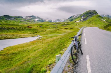 Norveç dağları sahnesinde aktif ekipman ile Bisiklet. Dağda bisiklet. Bisiklet Dağlara Karşı Yolda Park Etti. Norveç dağlarında bisiklet turizmi, İskandinavya ve Avrupa aktif yaşam