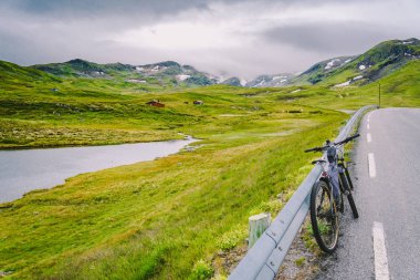 Norveç dağları sahnesinde aktif ekipman ile Bisiklet. Dağda bisiklet. Bisiklet Dağlara Karşı Yolda Park Etti. Norveç dağlarında bisiklet turizmi, İskandinavya ve Avrupa aktif yaşam