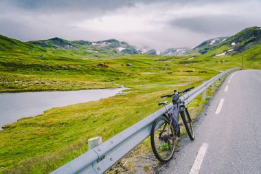 Norveç dağları sahnesinde aktif ekipman ile Bisiklet. Dağda bisiklet. Bisiklet Dağlara Karşı Yolda Park Etti. Norveç dağlarında bisiklet turizmi, İskandinavya ve Avrupa aktif yaşam